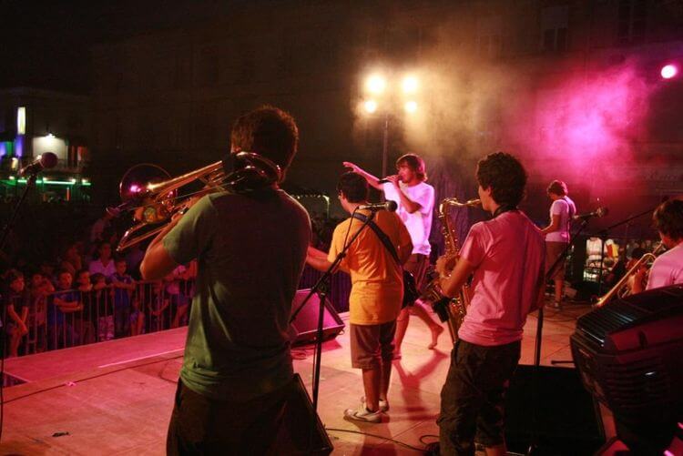 un chanteur sur scène avec ses musiciens au festival Escota é Minja à l’Isle-Jourdain.